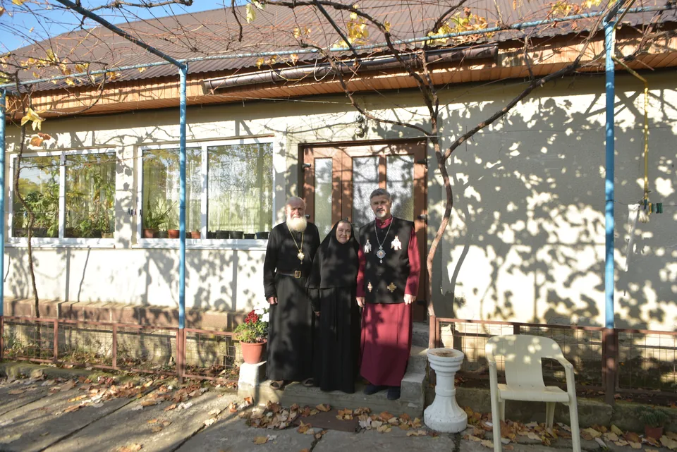 A building with a porch and people from the community in front of it