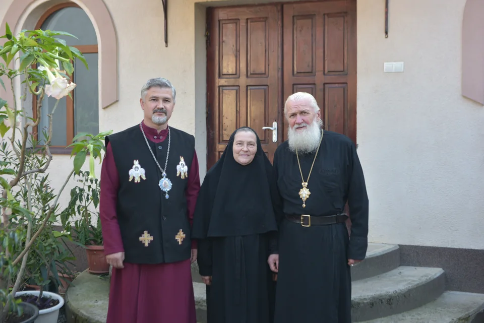 Троє людей із громади біля дерев’яних дверей будівлі