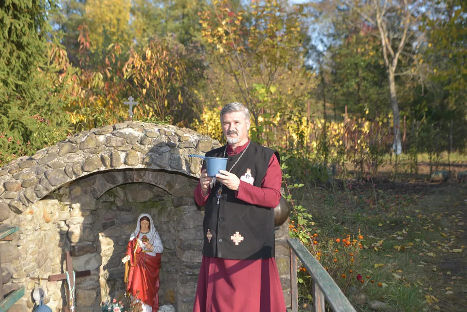 A clergy member with a glass beside a stone niche