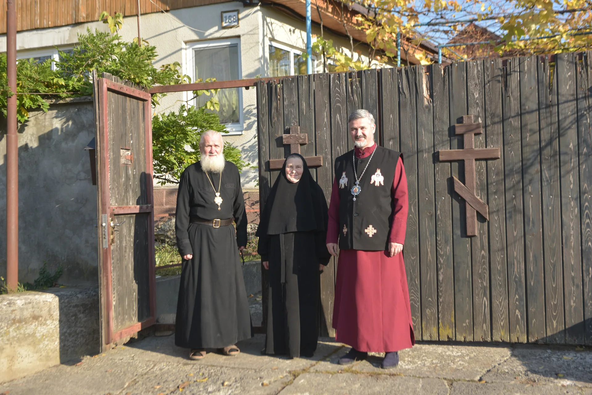 Three people from the community beside an open wooden gate