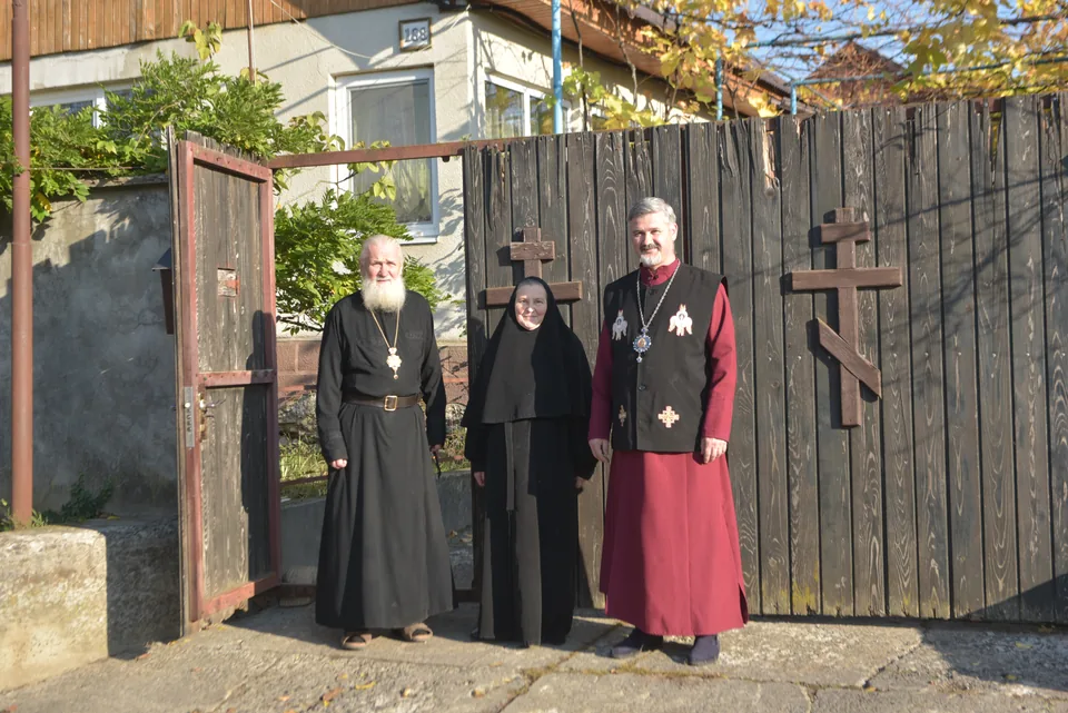 Three people from the community beside an open wooden gate